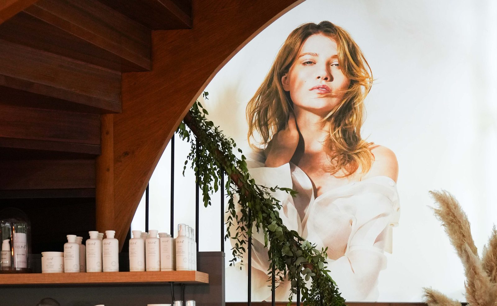 Le salon Unic by l'atelier des coiffés à Rennes : escalier en bois, étagères de soins Keune et grande affiche